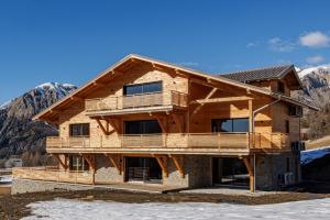 a log house with a mountain in the background at La Licorne de l'Encombrette 150 m2 in Allos