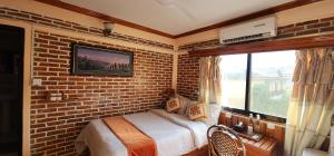 a brick walled bedroom with a bed and a window at Kiwi Backpackers Hostel Pokhara in Pokhara