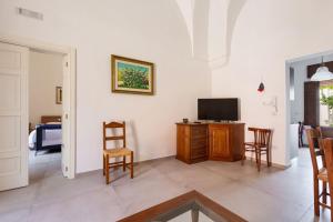 Una sala de estar con televisión, mesa y sillas. en Il Fico d`India by BarbarHouse, en Campi Salentina