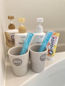 two cups with toothbrushes in them on a bathroom counter at 淺夏館Asakakan2 in Tokyo