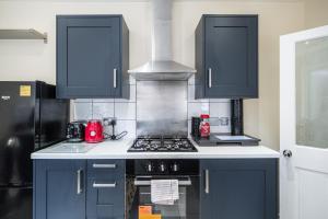 cocina con armarios azules y fogones en House - Sleeps 8 - Garden - Short Walk to Station, en Londres