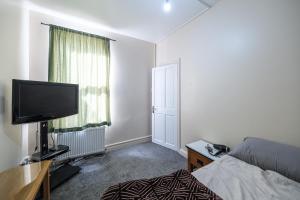 Un dormitorio con una cama y un televisor de pantalla plana. en House - Sleeps 8 - Garden - Short Walk to Station, en Londres