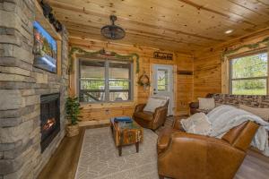 a living room with a stone fireplace in a log cabin at Tridents Creek by American Patriot Getaways in Rocky Grove