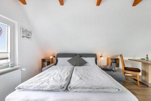 a bedroom with a large white bed and a chair at Huus achtern Diek - Ferienwohnung 5 in Nordstrand