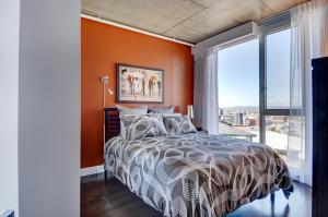 1 dormitorio con paredes de color naranja y 1 cama con ventana grande en Les Immeubles Charlevoix - Le 760-415, en Quebec