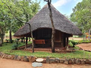 a small hut with a grass roof and a bench at Inkonka Game farm in Uitsig +6 photos