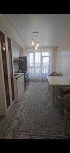 an empty living room with a table and a kitchen at Апартамент in Osh