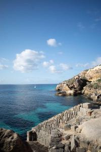 a stone wall next to the ocean with a boat at Villa MAE Favignana in Favignana