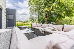 a patio with white couches and a table and trees at Das Strandhaus 2 in Lembruch