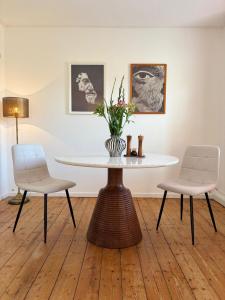 a dining room table with two chairs and a vase with flowers at Holistic Home Ökologisch-Biologisch-Philosophisch in Höhr-Grenzhausen