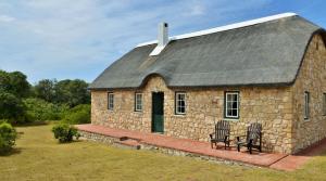 a stone house with two chairs in front of it at Melkkamer Foremans Cottage in De Hoop Nature Reserve