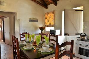 a kitchen with a table with chairs and a stove at Melkkamer Foremans Cottage in De Hoop Nature Reserve