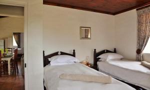 a bedroom with two beds and a dining room at Melkkamer Foremans Cottage in De Hoop Nature Reserve