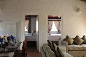 a living room with a couch and a room with two beds at Melkkamer Foremans Cottage in De Hoop Nature Reserve +1 photo