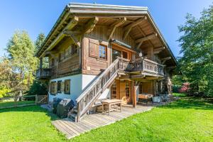 Una gran cabaña de madera con terraza y escaleras al porche. en Chalet White Moon, en Demi-Quartier