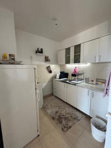 a kitchen with white cabinets and a sink and a refrigerator at Apartments Tibra in Sarajevo