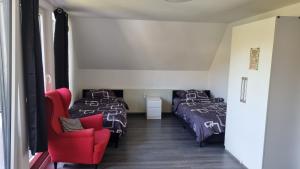 zwei Betten und ein roter Stuhl in einem Zimmer in der Unterkunft Mony land in Netphen