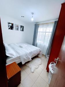 a small bedroom with a bed and a window at Elegant One Bedroom Apartment - Athi River - Kesit Anga in Athi River