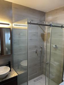 a bathroom with a glass shower with a sink at The Safehouse in Enugu