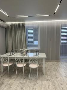 ein Esszimmer mit einem weißen Tisch und Stühlen in der Unterkunft Уютная квартира студия 72 кв in Oral