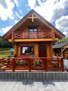 a log cabin with a wooden fence and flowers at Domki z bali na miedzy in Piwniczna