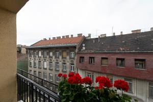 a window with red flowers on a balcony with buildings at Monroe Central Budapest in Budapest