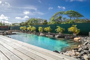 a pool of water with palm trees and a fence at Villa des Rochers in Saint-François