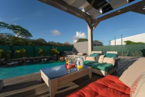 a patio with a couch and a table next to a pool at Villa des Rochers in Saint-François +28 photos