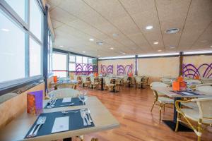 a dining room with tables and chairs and windows at Hotel Servigroup Rialto in Benidorm
