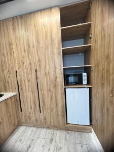 eine Küche mit Holzwänden und einer Tür mit Mikrowelle in der Unterkunft Уютная квартира студия 72 кв in Oral + 7 Fotos