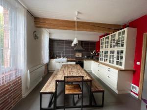 a kitchen with a large wooden table and red walls at Typical Toulouse house completely renovated in Launaguet