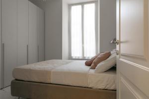 a bed in a white room with a window at Appartamento in Piazza Colombo a 300mt dal Mare in Sanremo