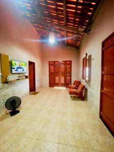 a living room with a couch and a tv on a wall at Jfhouse beach in Cascavel