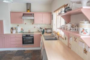 a pink kitchen with pink cabinets and a sink at Corner Cottage in Castlerock