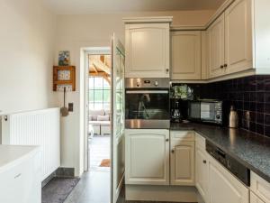 Una cocina con gabinetes blancos y un horno de estufa. en Beach Home with Bubble Bath, en Middelkerke