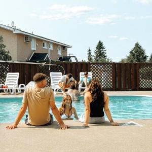 a group of people sitting around a swimming pool at Auberge Matha in Saint-Jean-de-Matha