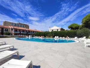 a pool with white chairs and people sitting around it at Residence Porto Sole in Cavallino-Treporti