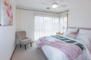 Un dormitorio con una cama y una silla y una ventana. en Stylish 3BR Walk to Town, en Trentham