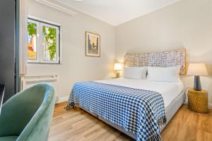 a bedroom with a bed and a green chair at Casa do Patio by Shiadu in Lisbon