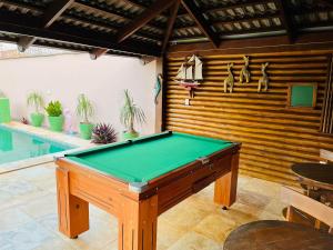 a pool table in a room next to a swimming pool at 4let Chalés Sonho de Verão in São Miguel do Gostoso
