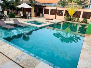 a swimming pool with two chairs and an umbrella at 4let Chalés Sonho de Verão in São Miguel do Gostoso