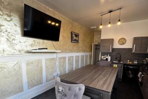 a kitchen with a table and a television on the wall at Central Sheffield 3-Bed Apt Sleeps 6 with Parking in Sheffield
