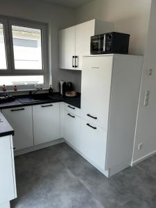a white kitchen with a microwave on top of a refrigerator at Ferienwohnung - Haus mit Faßsauna - Nähe Fulda in Großenlüder