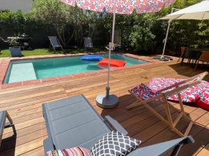a swimming pool with an umbrella and chairs at Typical Toulouse house completely renovated in Launaguet