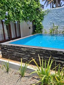 a swimming pool in a garden with a brick retaining wall at Haven house with AC in Kamburugamuwa