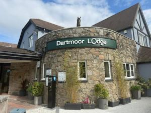 een stenen gebouw met een bord voor Adain Mirror Lodge bij Dartmoor Lodge Hotel in Ashburton