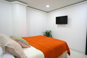 a white room with a bed with an orange blanket at Hogar De Ensueño in Envigado