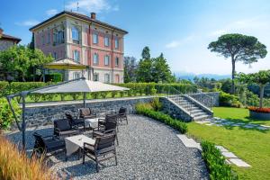a table with chairs and an umbrella in front of a building at Relais & Spa Castello di Casiglio in Erba