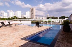 a swimming pool with chairs and a table and buildings at Perfect Campolim loft in Sorocaba