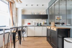 a kitchen with white cabinets and a black counter top at ParisConciergerie - 1BR apartment with AC in Paris